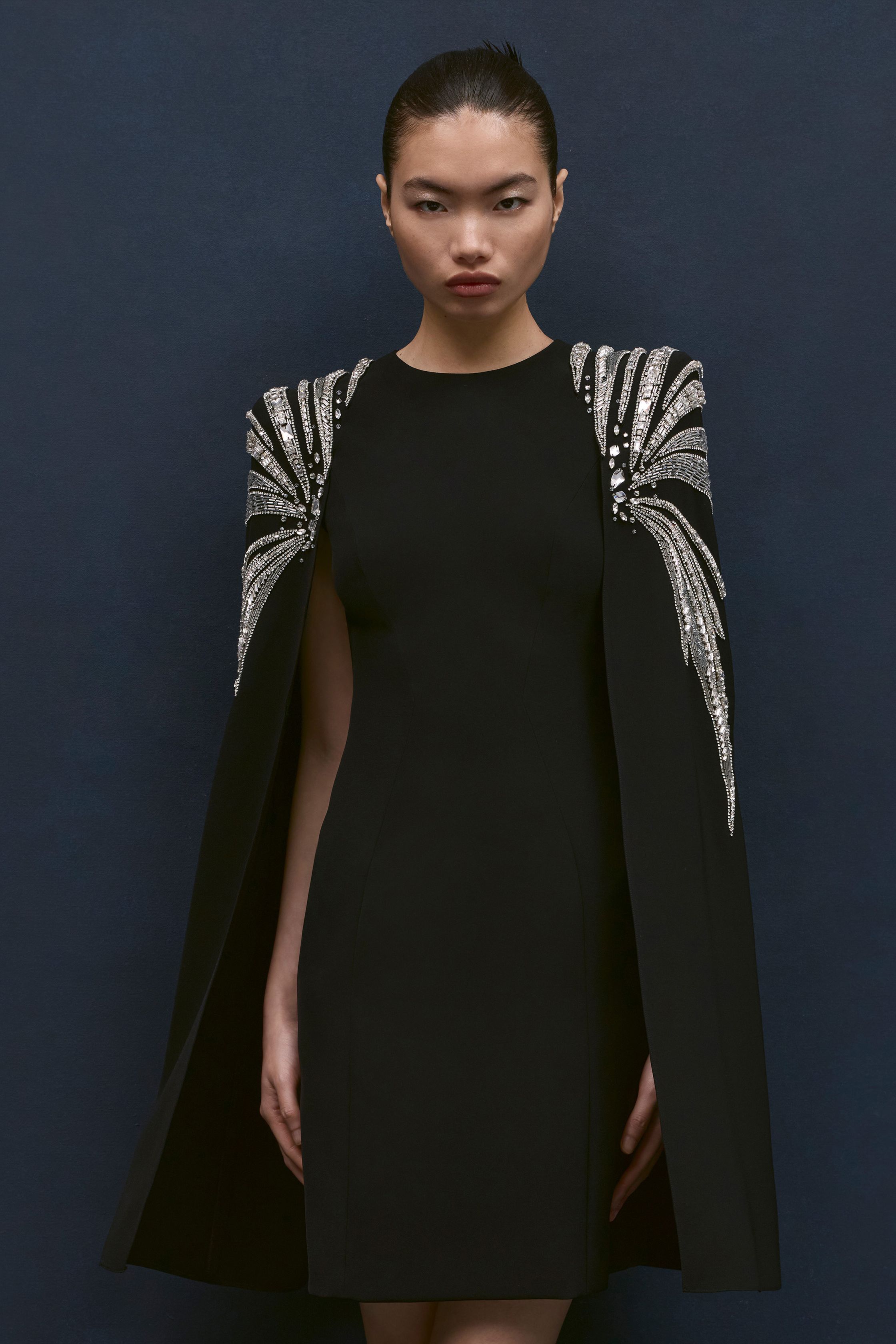 Jenny Packham本季延续品牌标志性的红毯礼服风格，以闪耀流苏、金属光泽与修身长裙构建极具戏剧感的夜晚造型。银色亮片与深蓝礼服形成冷艳优雅的视觉对比，垂坠流苏与贴身剪裁让服装在行走间呈现波光般的流动感。设计在极简轮廓中加入华丽装饰，使整个系列既保留经典好莱坞 glamour，又展现现代女性的自信与优雅-顽石频道趋势研究